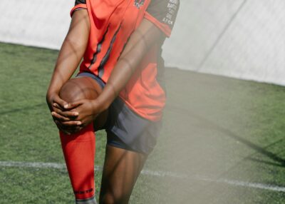 Young soccer player stretching before practice on a grassy field.
