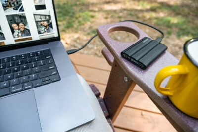 Laptop, external hard drive, and mug on chair