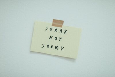 Minimalist post-it note taped to wall with phrase 'Sorry Not Sorry'.